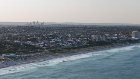 Luftaufnahme-Der-Skyline-Von-Perth-In-Zeitlupe-Mit-Dem-Strand-Von-Scarborough-Im-Vordergrund