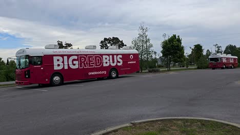 Oneblood-big-red-bus-blood-donation-vehicles-sit-in-parking-lot-behind-facility