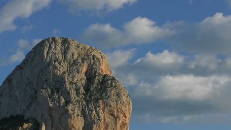 Timelapse-Pina-De-IFac-rock-climbing-face-in-warm-winter-evening-sunshine-blue-sky-and-clouds-drifting-by