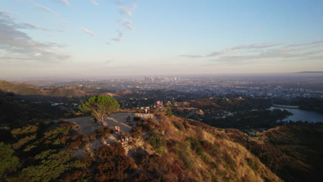 A-Cinematic-Aerial-Shot-of-Los-Angeles-at-Golden-Hour,-Pushing-Past-Wisdom-Tree-and-the-Hollywood-Reservoir