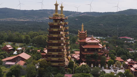 Aerial-of-traditional-south-east-asia-buddhist-temple-zen-tradition-with-windmill-turbine-in-background,-climate-change-human-development-concept