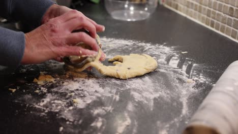Close-up-shot-of-a-baker-using-a-rolling-pin-and-cookie-cutter-on-a-scone-mixture