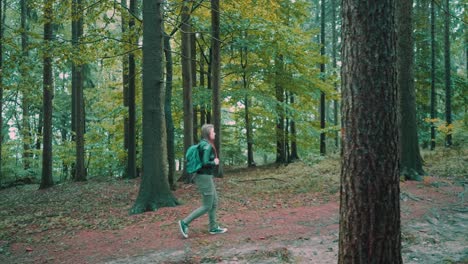 Female-with-backpack-hiking-through-dense-forest-following-countryside-trail