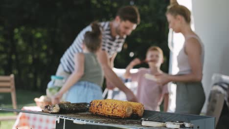 Video-of-grilled-corn-against-the-background-of-bustling-family