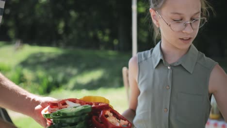 Tracking-Video-Von-Tochter,-Die-Beim-Anrichten-Von-Gemüse-Auf-Dem-Grill-Hilft