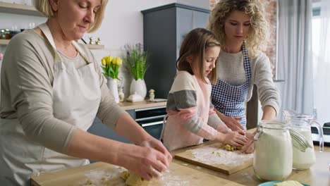 Video-of-three-generations-of-women-kneading-dough-in-kitchen
