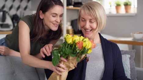 Daughter-giving-her-mother-flowers-and-gift-card