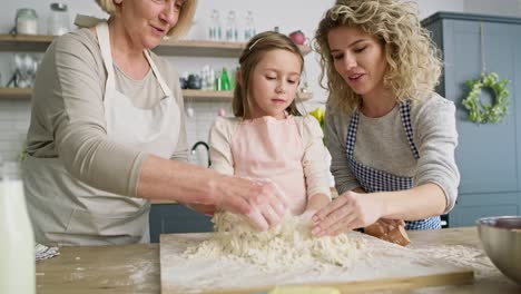 Front-view-of-girl-with-mom-and-grandma-making-dough