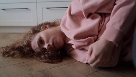Zoom-in-video-of-depressed-young-caucasian-woman-lying-in-the-floor.