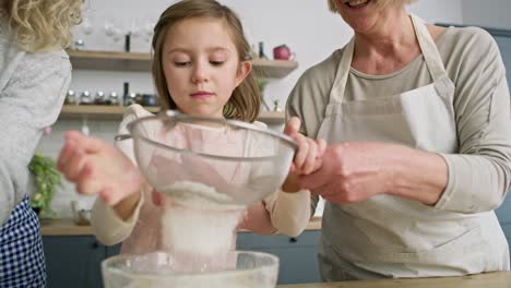Handheld-video-of-girl-with-mother-and-grandmother-sifting-flour