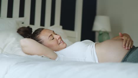 Handheld-video-of-cheerful-pregnant-woman-relaxing-in-bed.