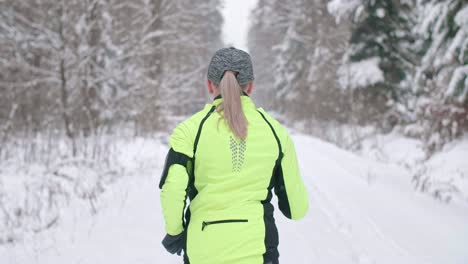 Rear-view-of-woman-running-in-winter-forest