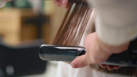Handheld-view-of-hairdresser-using-straightener-and-comb