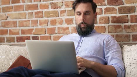 Video-De-Un-Hombre-Con-Una-Camisa-Sentado-Y-Usando-Una-Computadora-Portátil