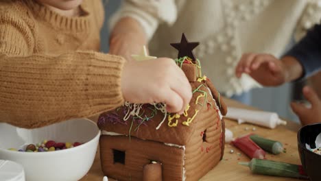 Tilt-down-video-of-family-decorating-together-gingerbread-house