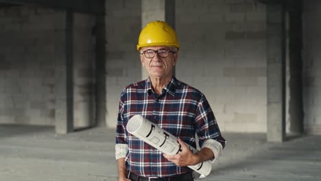 Portrait-of-caucasian-senior-engineer-holding-plans-and-standing-on-construction-site.
