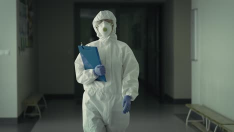Handheld-video-of-worker-in-protective-suit-walking-down-the-hall