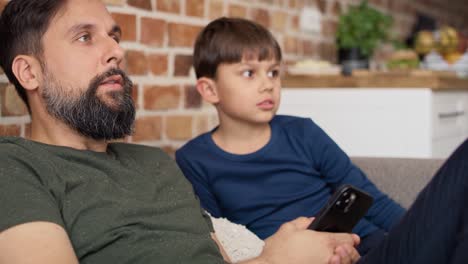 Close-up-video-of-father-and-son-watches-TV-at-home