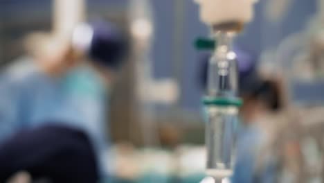 Intravenöse-Infusion-Und-Beschäftigte-Chirurgen-Im-Hintergrund
