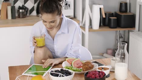 Young-woman-using-a-tablet-during-breakfast