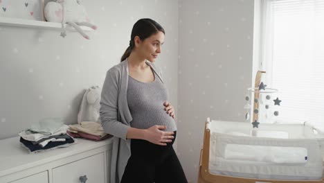 Mujer-Caucásica-Reflexiva-En-Embarazo-Avanzado-Parada-En-La-Habitación-Del-Bebé-Al-Lado-De-La-Cuna.