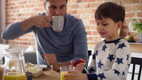 Video-of-father-and-son-eating-breakfast-together-at-the-morning