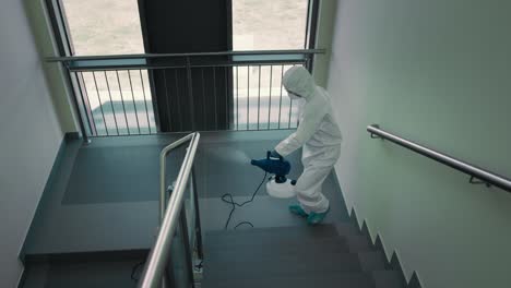Top-view-of-person-in-protective-suit-disinfecting-the-staircase