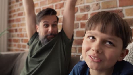 Video-of-father-and-son-playing-video-game-on-couch