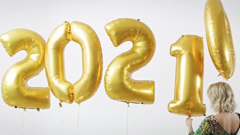 Frau-Mit-Goldenen-Luftballons-Baut-Die-Figur-„2021“
