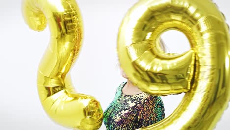 Junge-Frau-Mit-Goldenen-Luftballons-Baut-Die-Figur-„29“