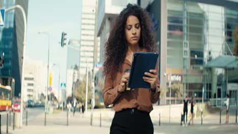 Video-of-smiling-businesswoman-walking-with-a-tablet-and-coffee