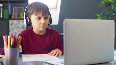 Handheld-video-of-boy-with-headphones-during-remote-learning-at-home