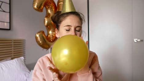 Birthday-girl-blowing-a-gold-balloon