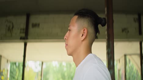 Seitenansicht-Eines-Jungen-Chinesischen-Mannes,-Der-In-Ein-Verlassenes-Gebäude-Geht