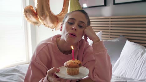 Disappointed-woman-blowing-out-the-candle-on-the-birthday-cupcake