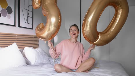 Portrait-of-young-woman-with-balloons-spending-birthday-time-in-bed