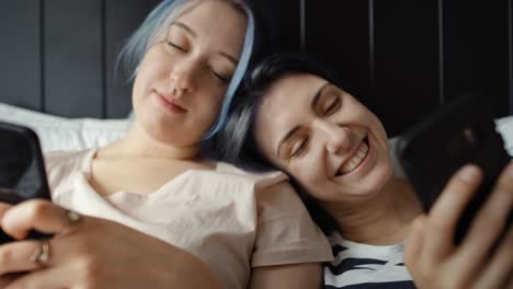 Front-view-video-of-women-lying-with-phones-in-bed.
