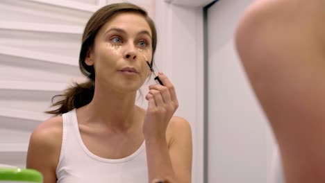Woman-applying-concealer-on-her-face-in-bathroom