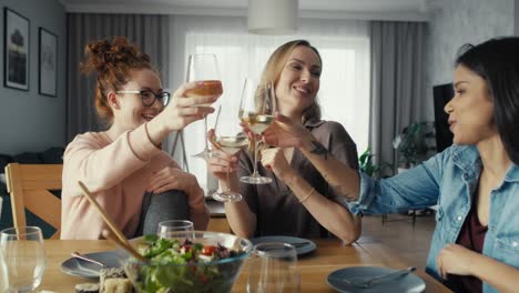 Three-female-caucasian-friends-chatting-and-drinking-wine-at-home