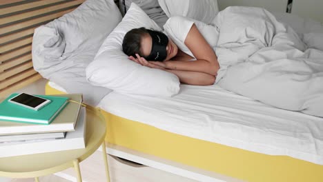Woman-with-eye-mask-sleeping-in-bedroom