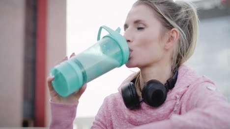 Handheld-view-of-woman-drinking-protein-drink-after-workout