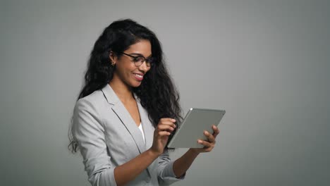 Young-smiling-businesswoman-uses-a-digital-table-in-studio-shot