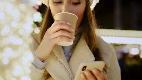 Close-up-video-of-woman-drinking-mulled-wine-and-browsing-phone
