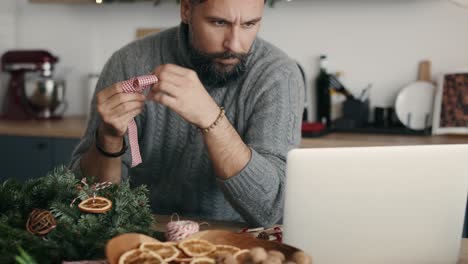 Man-looking-on-online-guide-how-to-make-Christmas-decorations
