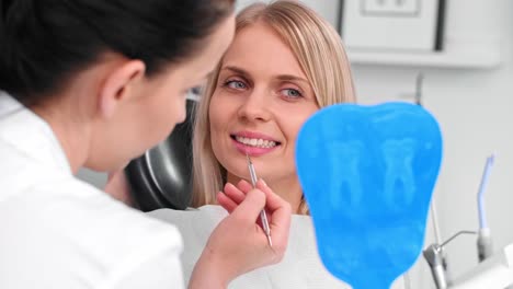 Dentist-examining-woman's-teeth-in-dentist's-office