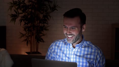 Playful-man-using-a-laptop-at-night