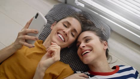 Top-view-of-women-lying-on-the-floor-with-phone