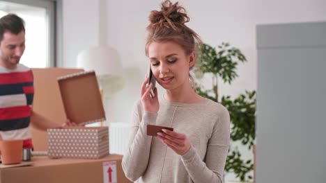 Smiling-woman-using-phone-while-moving-house