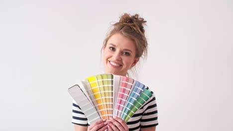 Portrait-of-smiling-woman-showing-paint-swatches