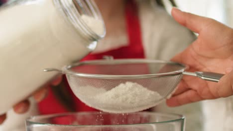 Close-up-of-woman-sifting-flour-through-sieve